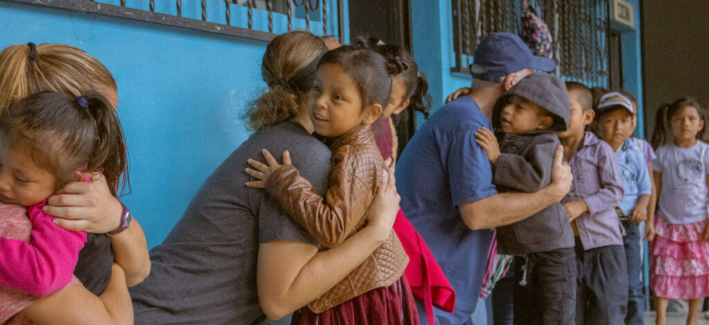 Guatemalan children receiving hugs from members of a mission team